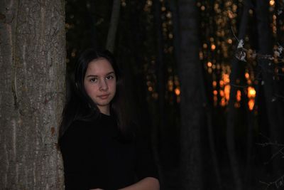 Portrait of teenage girl on tree trunk in forest