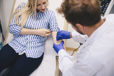 High angle view of young male doctor rubbing on female patient's hand at hospital