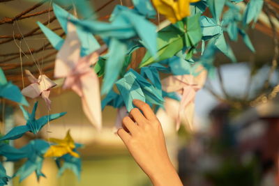 Cropped hand touching paper crane