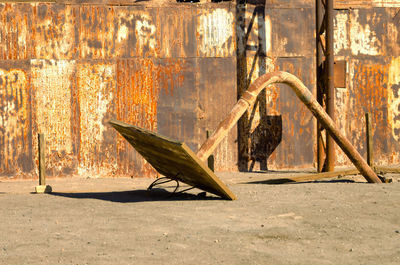 Close-up of fallen basketball hoop against rusty corrugated iron outdoors