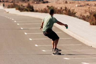 A man playing figure skating on a rural road in the sun on a bright day, play surf skate