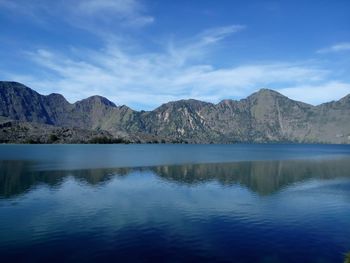 Scenic view of segara anak lake by mountains against sky