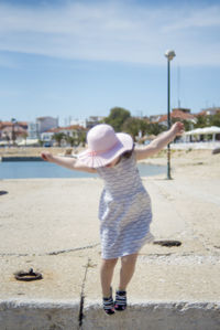 Rear view of boy standing on beach against sky