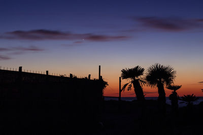 Silhouette palm trees against sky during sunset