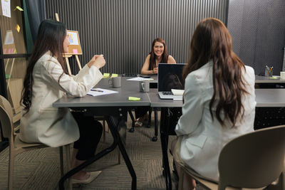 Young woman using mobile phone while sitting on table