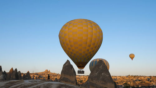 A balloon with tourists flying between two protruding rocks. 