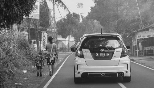 Rear view of people riding motorcycle on road in city