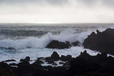 Waves crashing against black volcanic rock formations