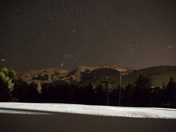 Scenic view of snowcapped mountains against star field at night