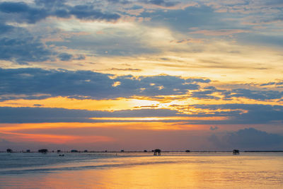 Scenic view of sea against dramatic sky during sunset