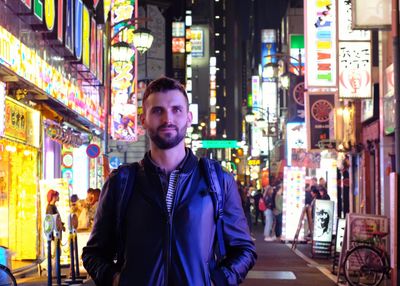 Portrait of young man standing in city at night