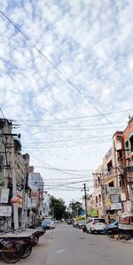 Cars on road by buildings in city against sky