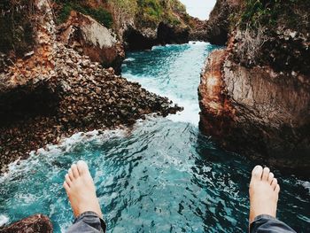 Low section of man standing on rock by sea