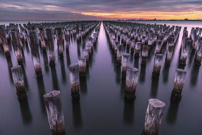 Panoramic shot of wooden posts in sea against sky
