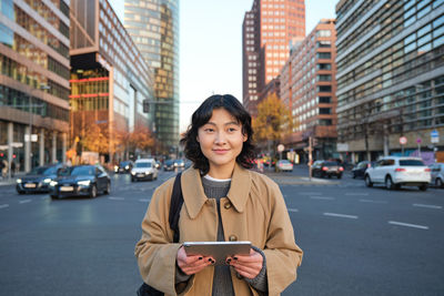 Portrait of young woman standing in city