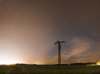 Electricity pylon on land against sky during sunset