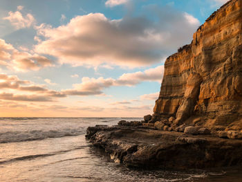 Rock formation on beach against sky during sunset