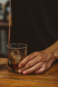 Midsection of man holding drink on table