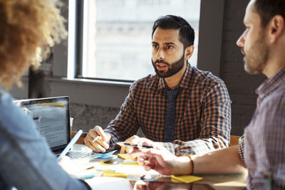 Colleagues discussing at desk in office