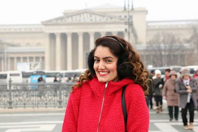 Portrait of smiling young woman standing on city street in foggy weather