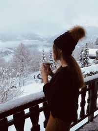 Woman standing by railing during winter