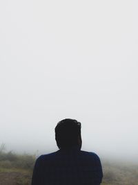 Rear view of man on landscape against clear sky