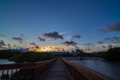 Pier on river against cloudy sky