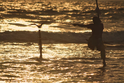 Silhouette of person and bird on beach