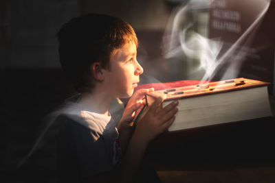 Redhaired boy looks at a magic book over which a cloud of ghost-shaped smoke rises. fantasy. 