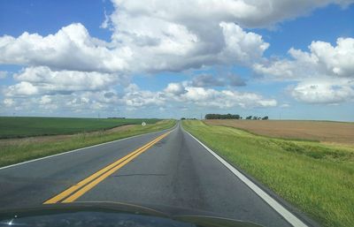 Road amidst field against sky