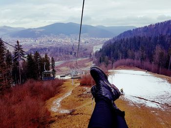 Low section of person on snow covered landscape against sky