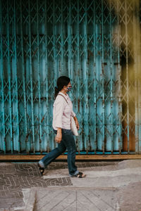 Side view of woman looking away while standing on footpath