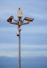 Low angle view of security camera against sky