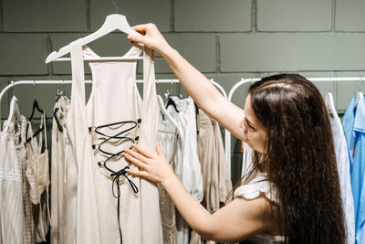 Modern latina young woman choosing 100 percent organic cotton wear in modern eco-friendly showroom.
