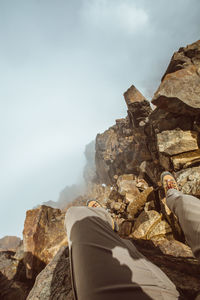 Low section of man standing on cliff during foggy weather