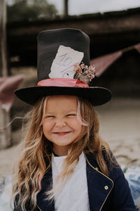 Child girl in jacket and top hat laughing at the beach