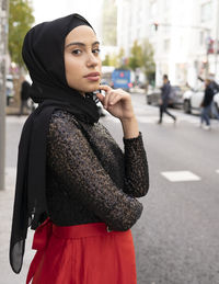 Portrait of young woman standing on street in city