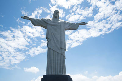 Low angle view of cross statue against cloudy sky