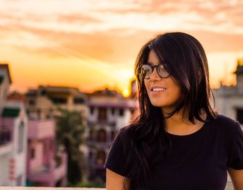Portrait of smiling young woman standing against sunset