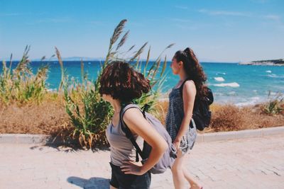 Young women walking on promenade against sky