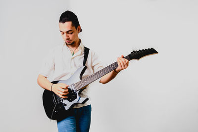 Young man playing guitar against white background