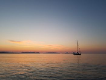 Sailboat in sea against sky during sunset