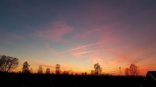 Silhouette trees on field against romantic sky at sunset