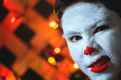 Close-up portrait of boy with face paint against illuminated light