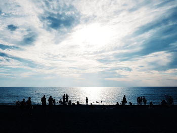 Silhouette people on beach against sky