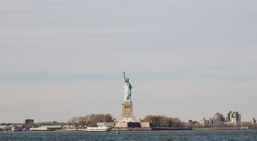 Statue in sea against sky