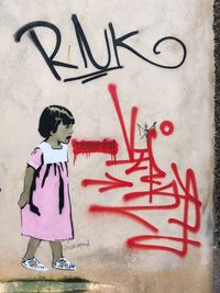 Full length of child standing by graffiti on wall