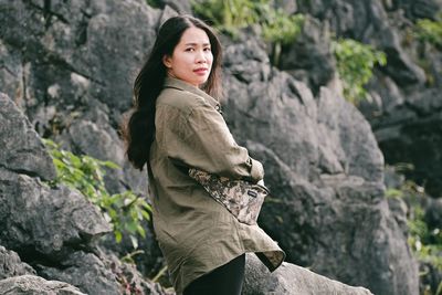 Portrait of young woman standing against rock
