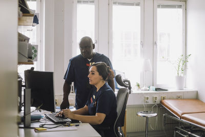 Female nurse explaining colleague over computer at hospital