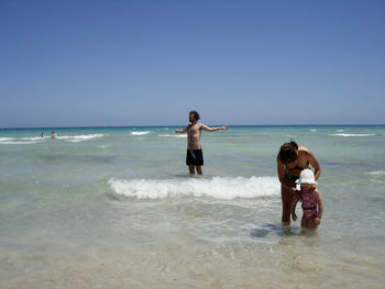 Friends on beach against clear sky